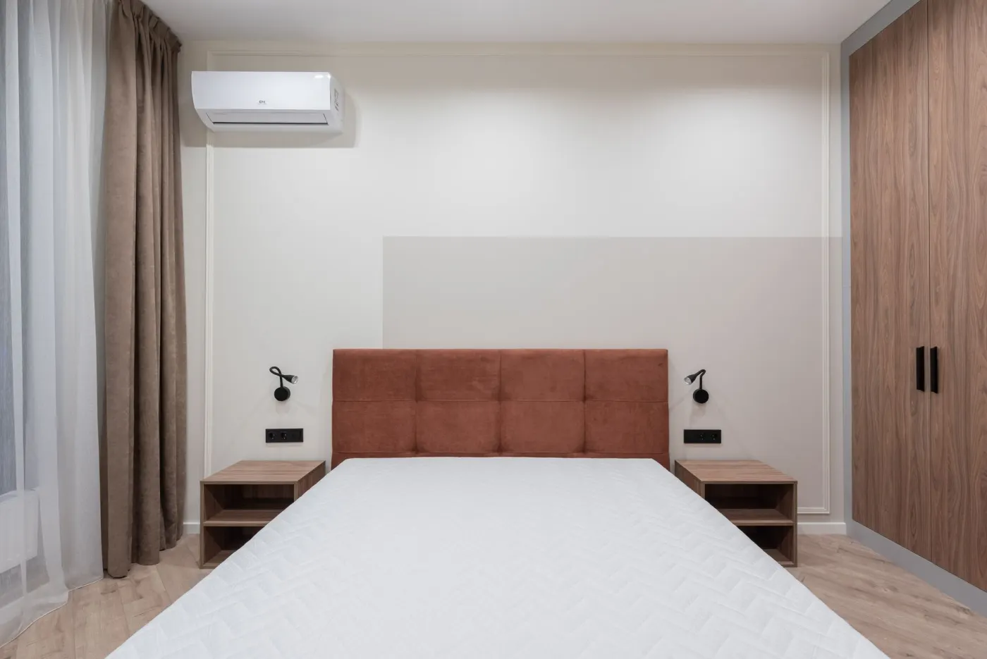Unité murale de climatisation dans une chambre, posée en hauteur à distance du lit